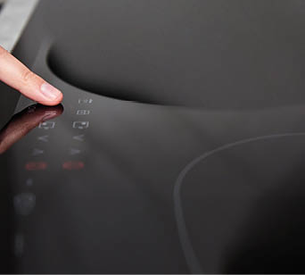 Modern kitchen appliance. Woman hand turn on induction stove to cook. Finger touching sensor button on induction or electrical hob