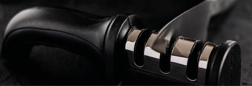 Grindstone and knife on dark background. Knife to fillet and hand held knife sharpener