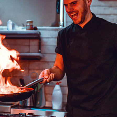 Male Chef Trying Out Oriental Flaming Recipe In Professional Kitchen