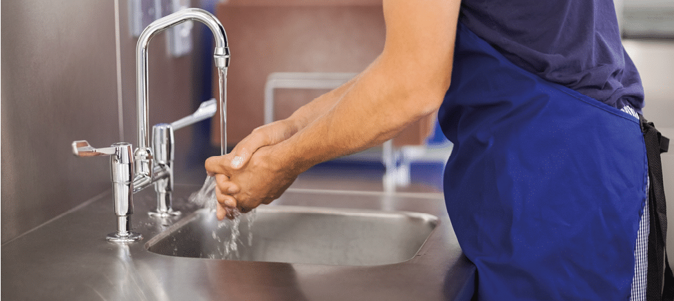 Kitchen porter washing his hands in professional kitchen
