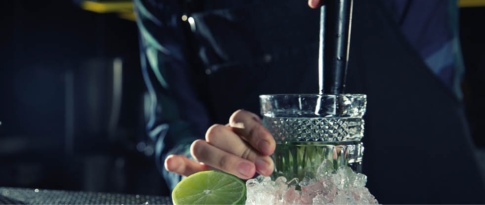 Barman making Mojito cocktail at counter in pub, closeup. Space for text