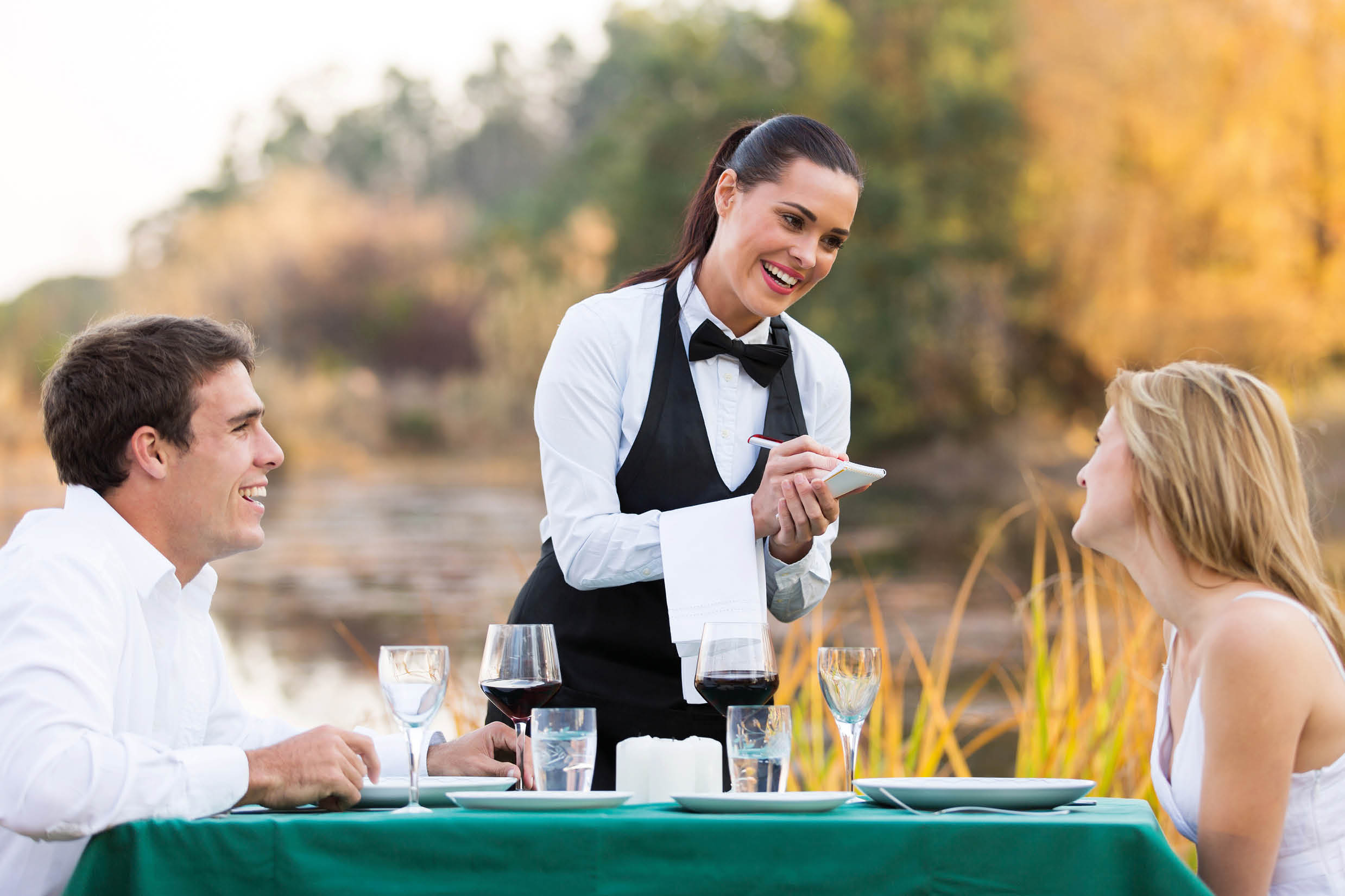 friendly female waitress taking order from cute young couple