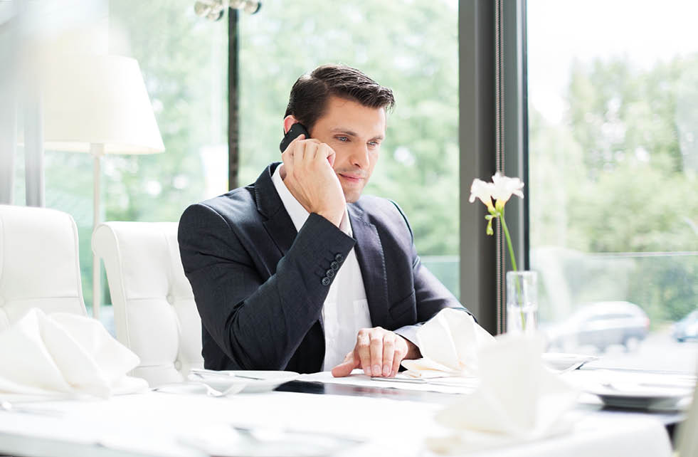 Handsome businessman talking over mobile phone in restaurant