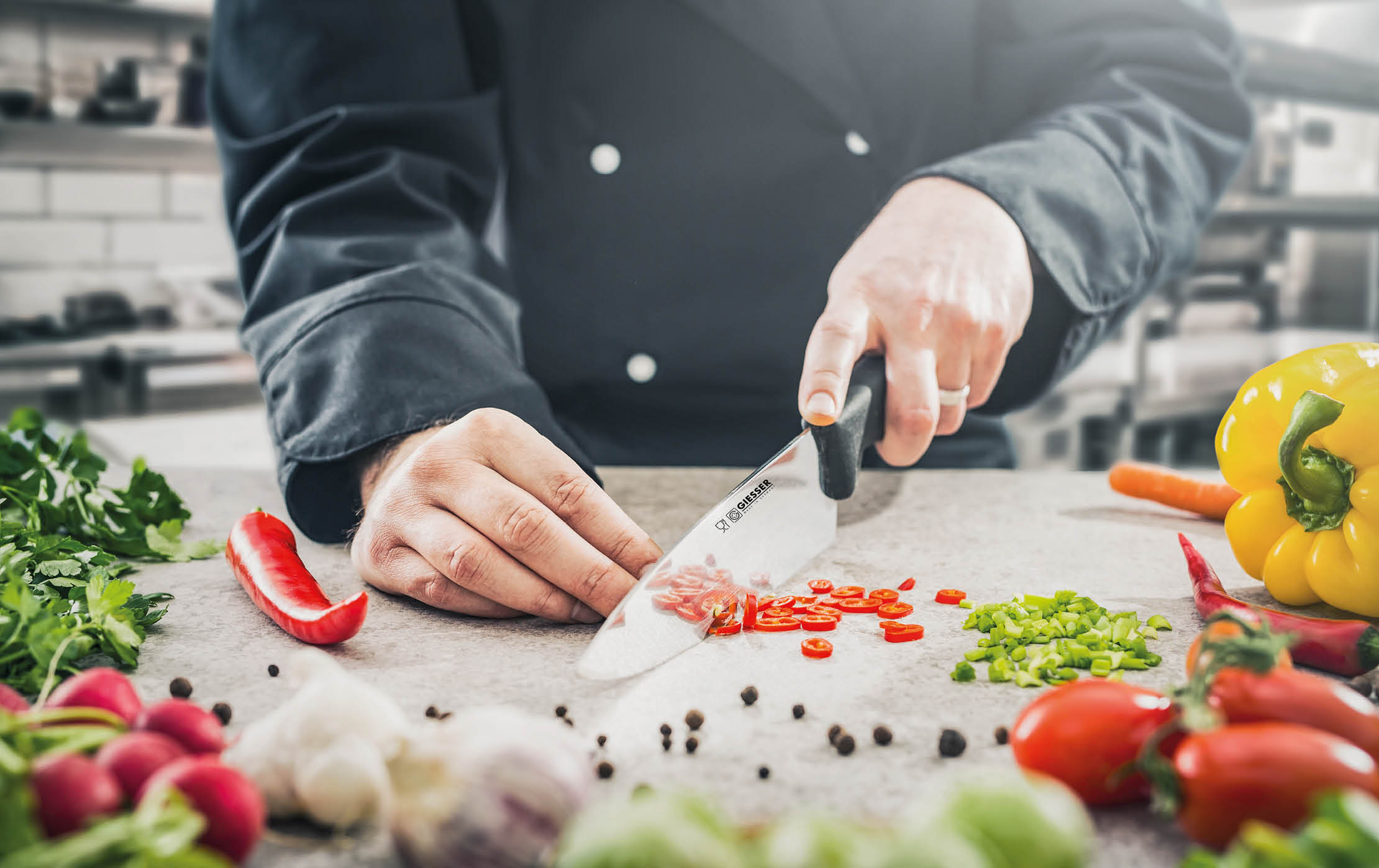 The chef in a black apron prepares the dish. Chopping vegetables in the kitchen.